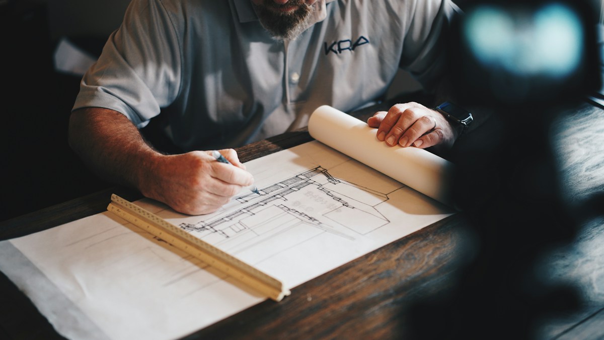 An architect working on blueprints with a pencil and ruler