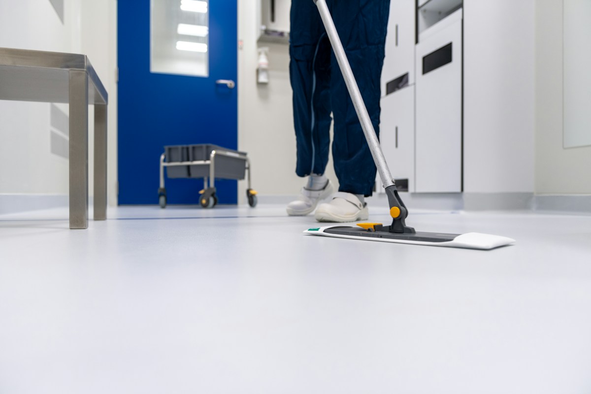 A person mopping the floor of a commercial hallway