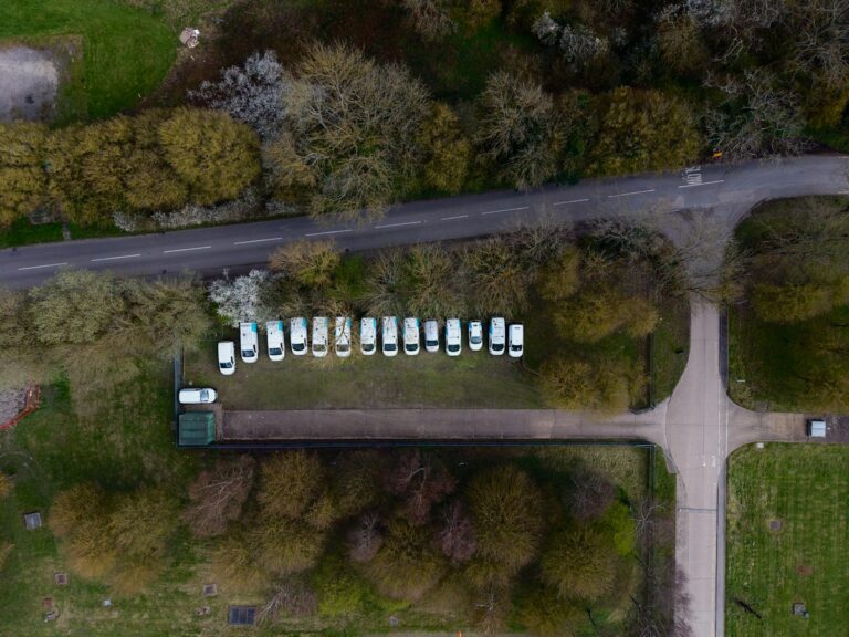 Aerial view of a fleet of white vans parked along a road