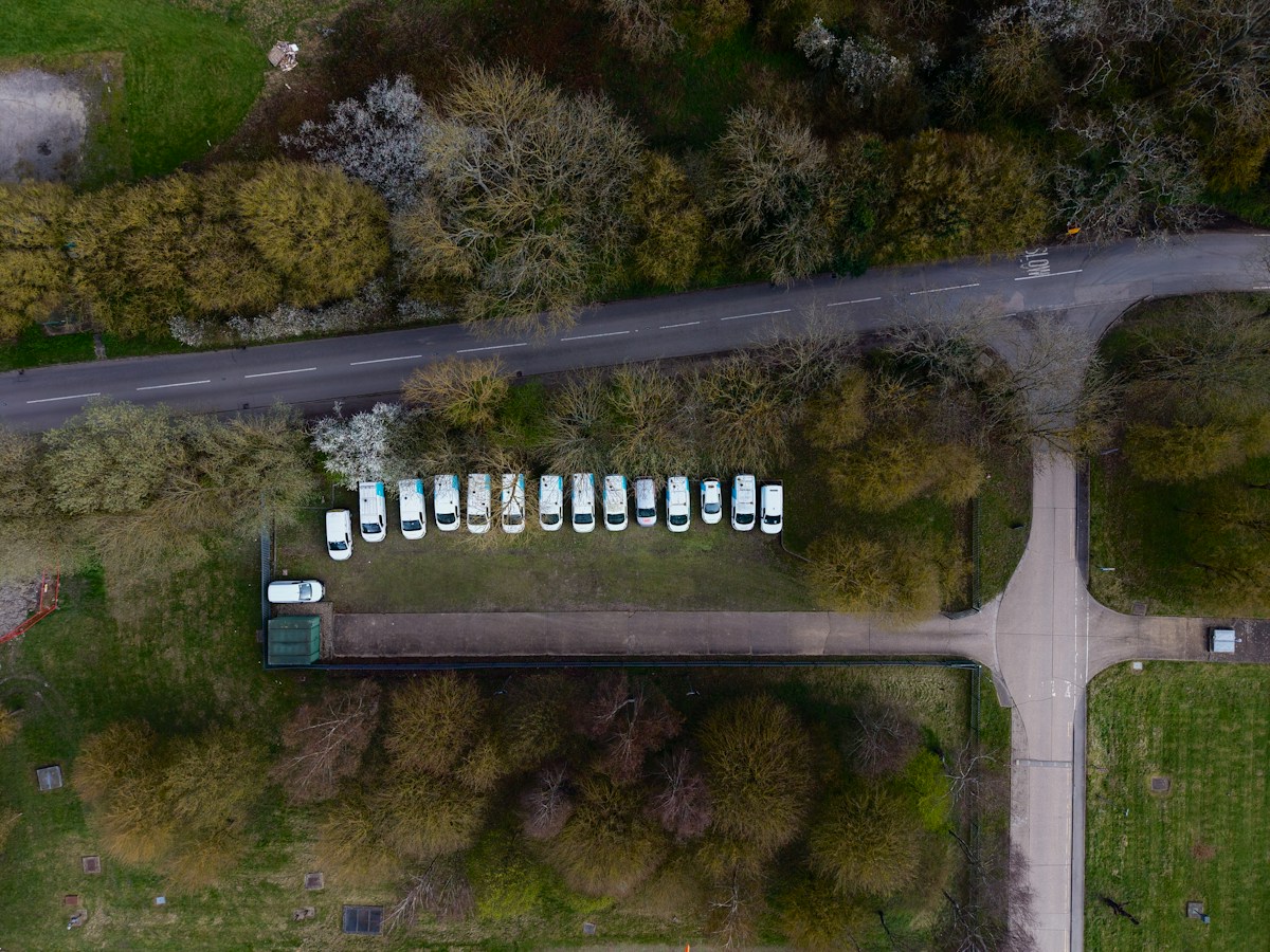 Aerial view of a fleet of white vans parked along a road