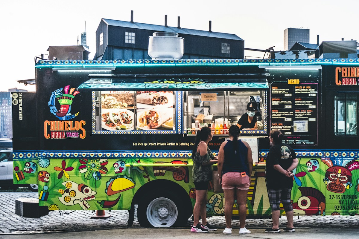 A group of people standing in front of a food truck