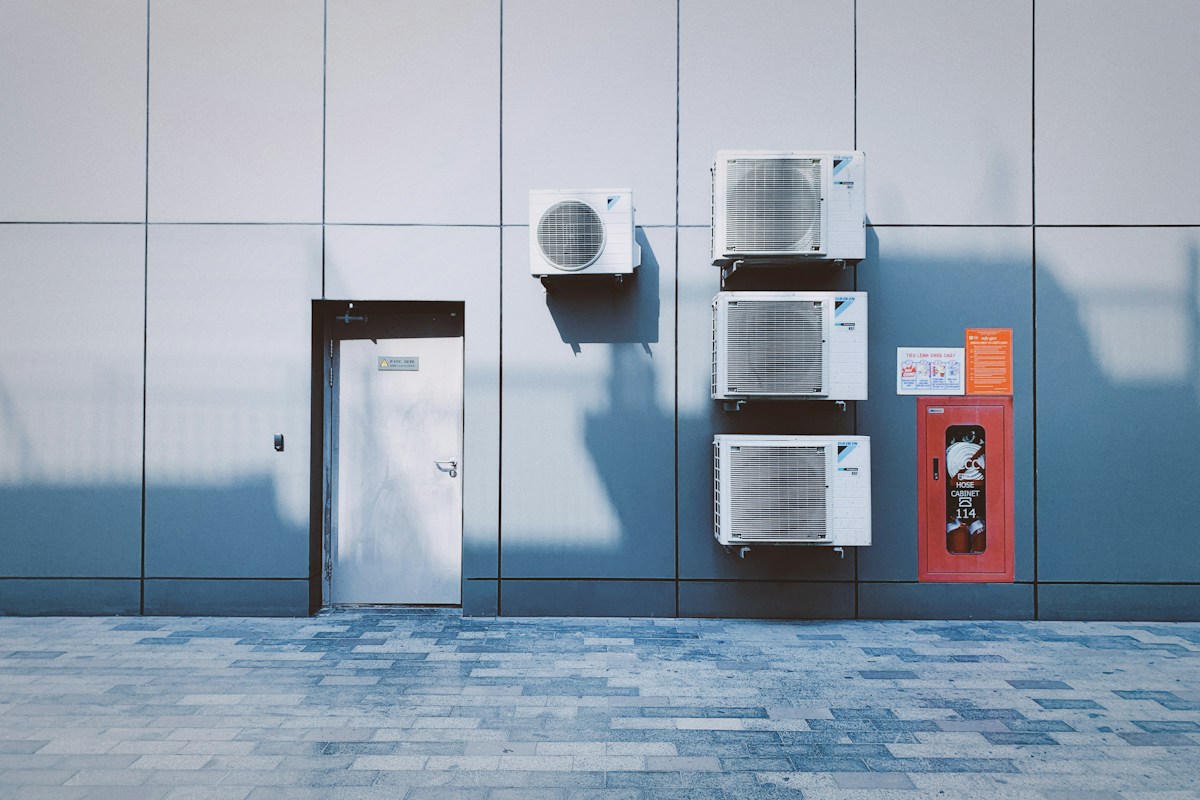 Four air conditioning units on a grey panelled wall