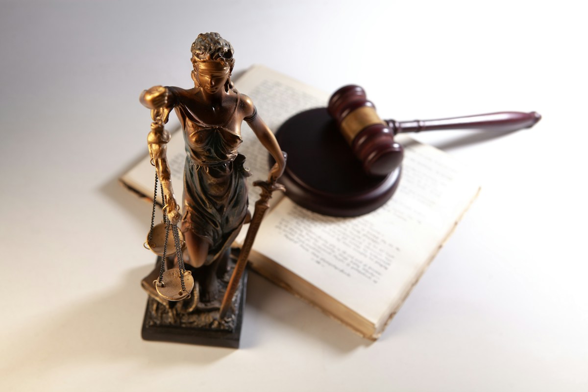 Statue of justice, gavel, and open law book on a table