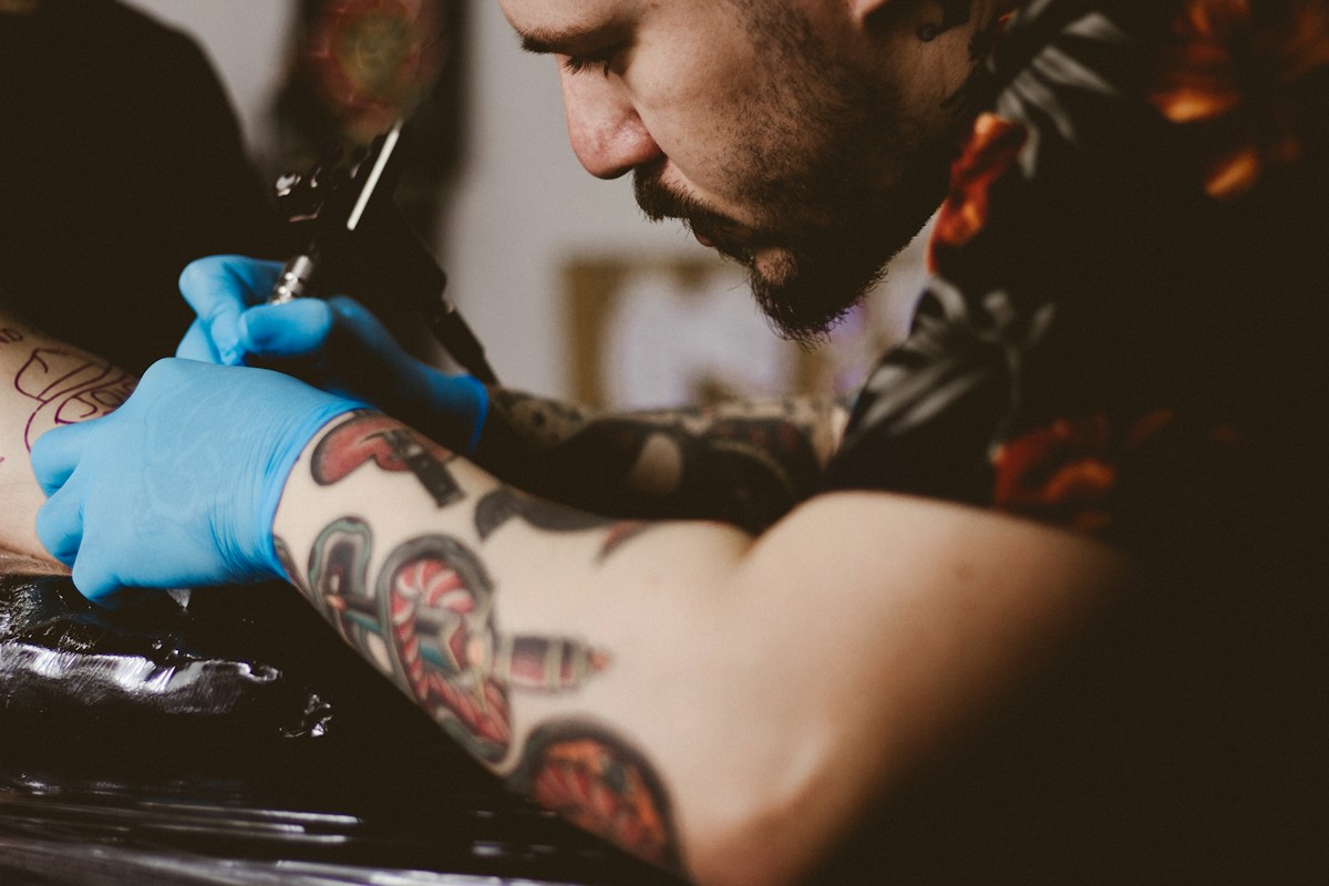 Tattoo artist tattooing a client arm